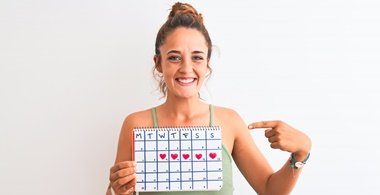 lächelndes Mädchen hält einen Periodenkalender in Händen