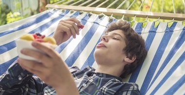 Junge isst Obst und liegt in der Hängematte