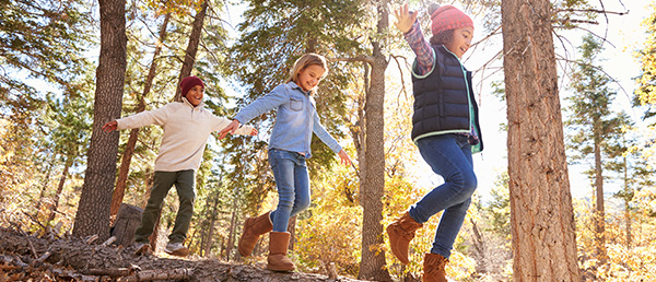 Kinder laufen auf Baumstamm